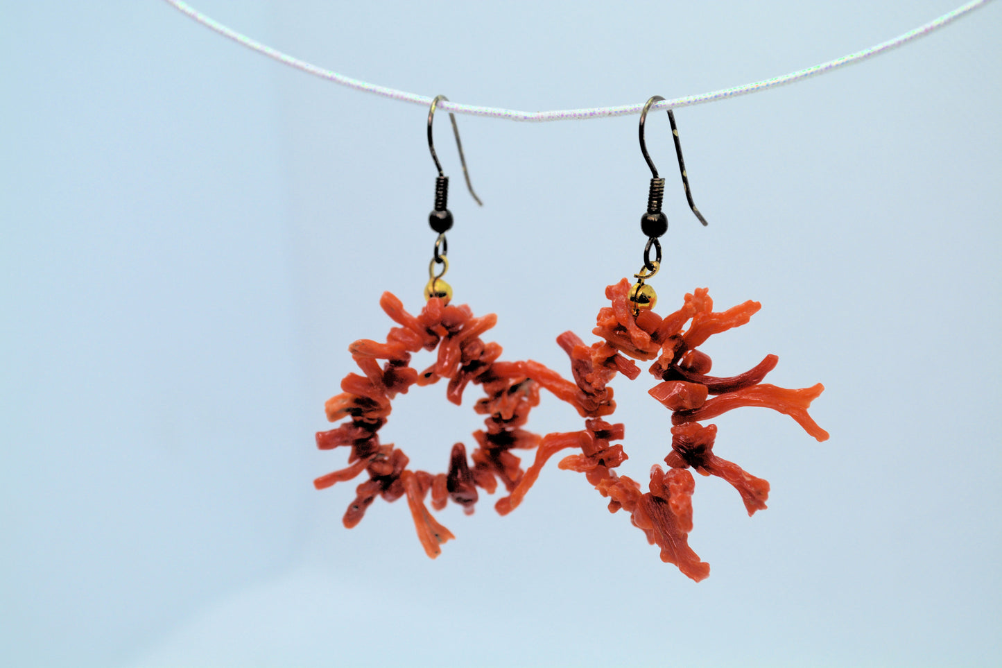 Red coral earrings on a light blue background