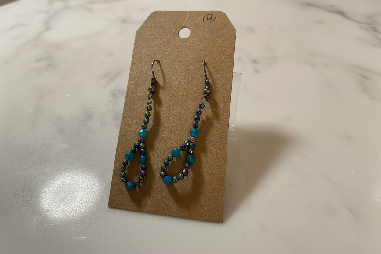 Pair of beaded earrings on a brown card against a marble background