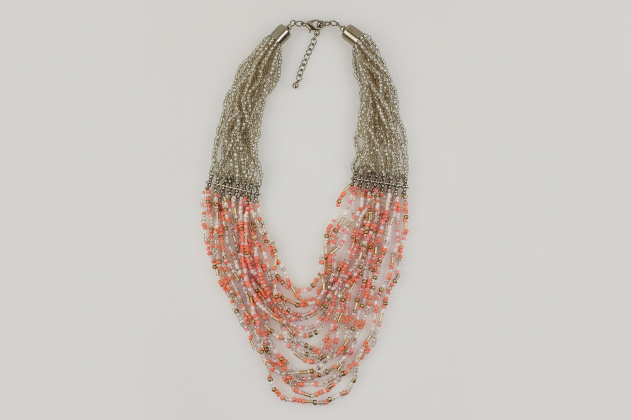 A multilayered beaded necklace with a mix of silver and pink beads, displayed on a white surface.