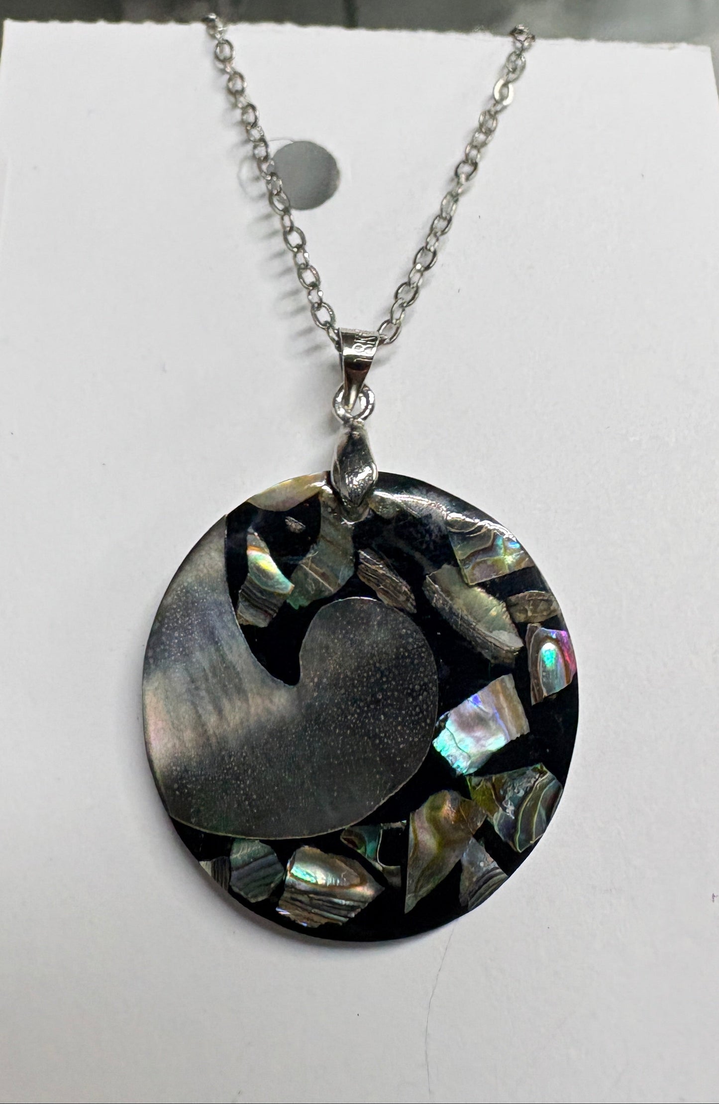 Necklace with a round pendant on a white card against a blurred background