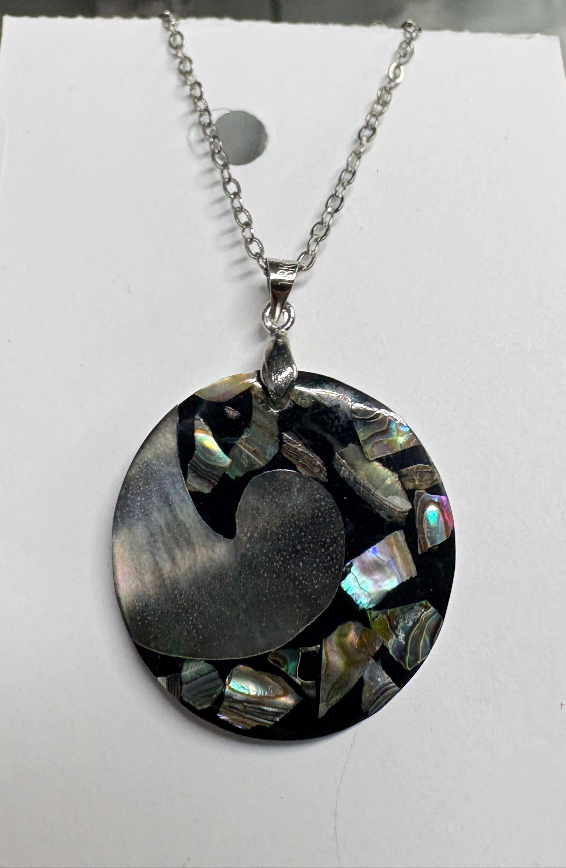 Necklace with a round pendant on a white card against a blurred background