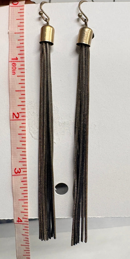 Two tassel earrings on a white card with a ruler for scale