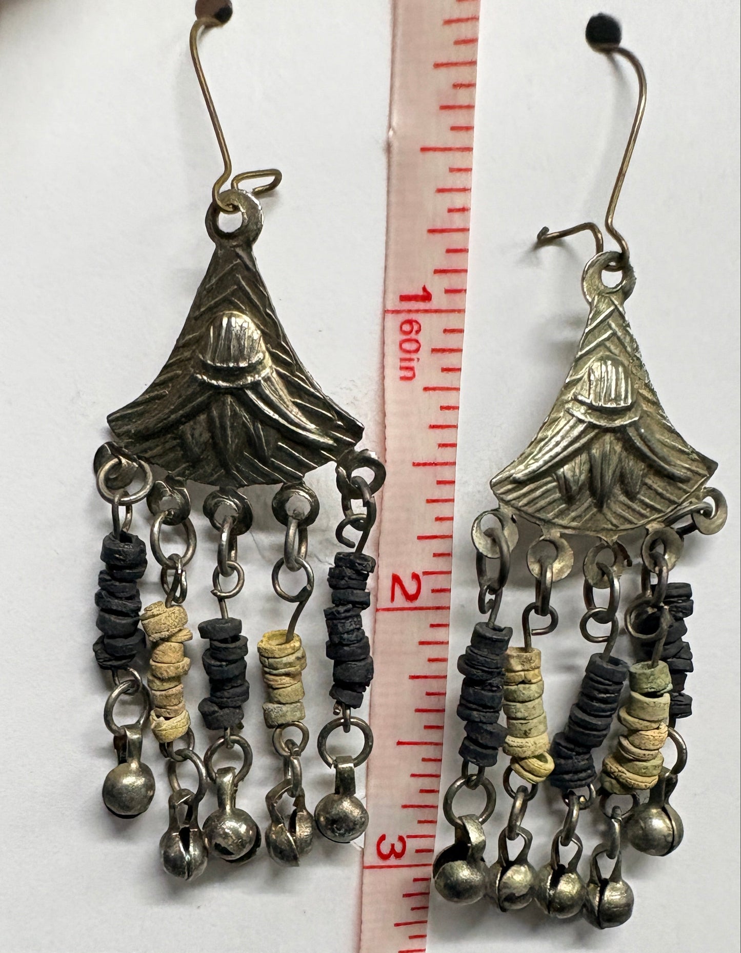 Decorative metal chain with beads on a white surface, measured against a ruler.