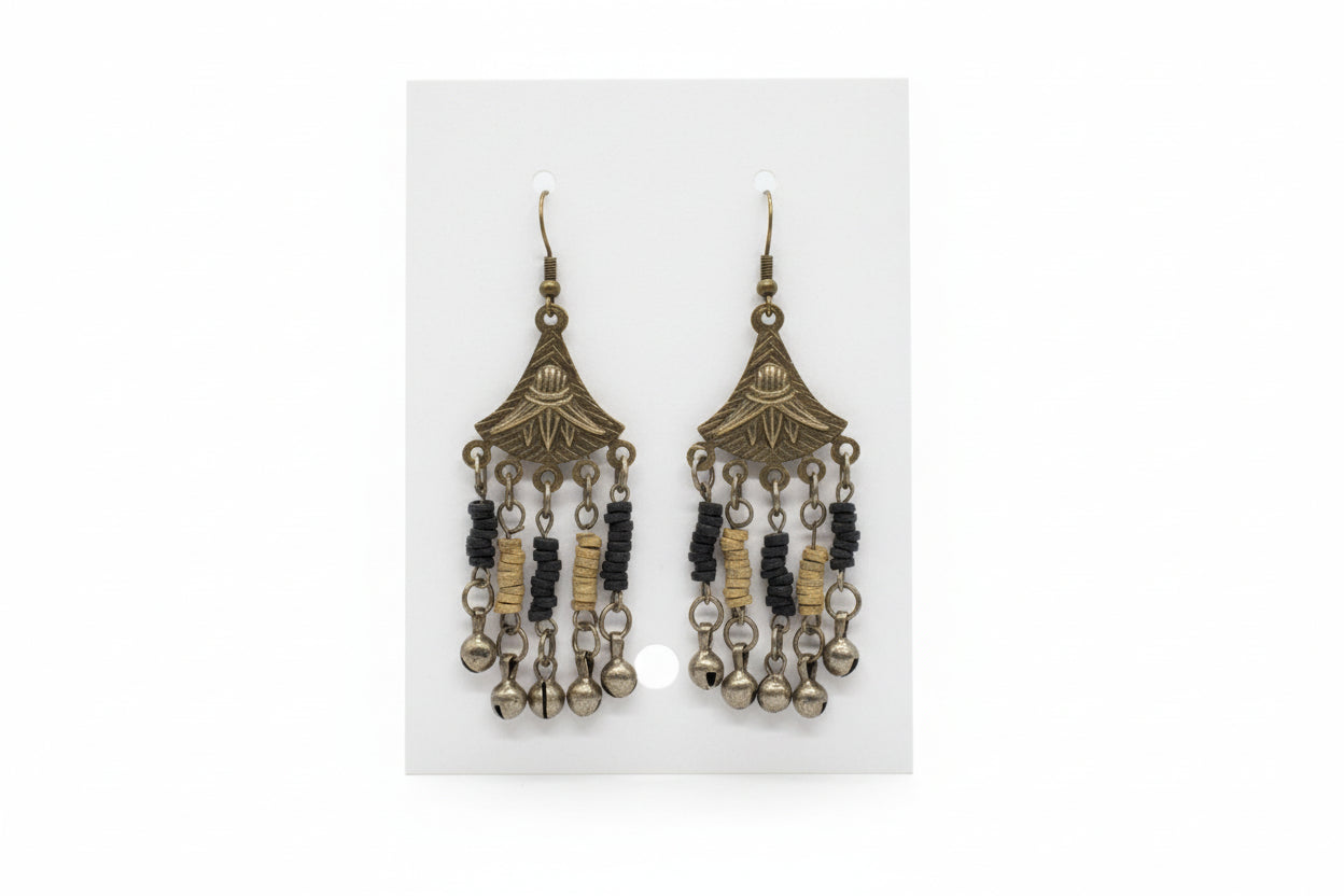 Pair of ornate earrings on a white card held by a hand against a neutral background