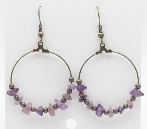 Amethyst beaded earrings on a white card held by a hand.