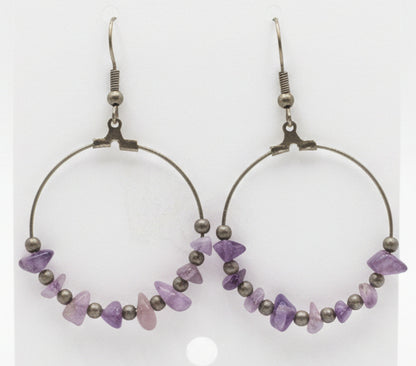 Amethyst beaded earrings on a white card held by a hand.