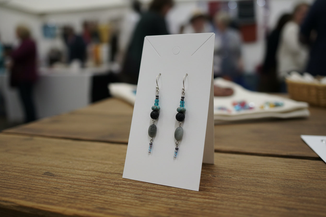 Pair of beaded earrings held by a hand on a white background