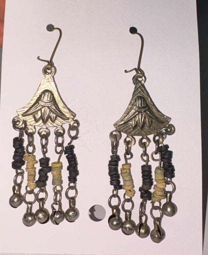 Pair of decorative earrings on a white card held by a hand against a neutral background