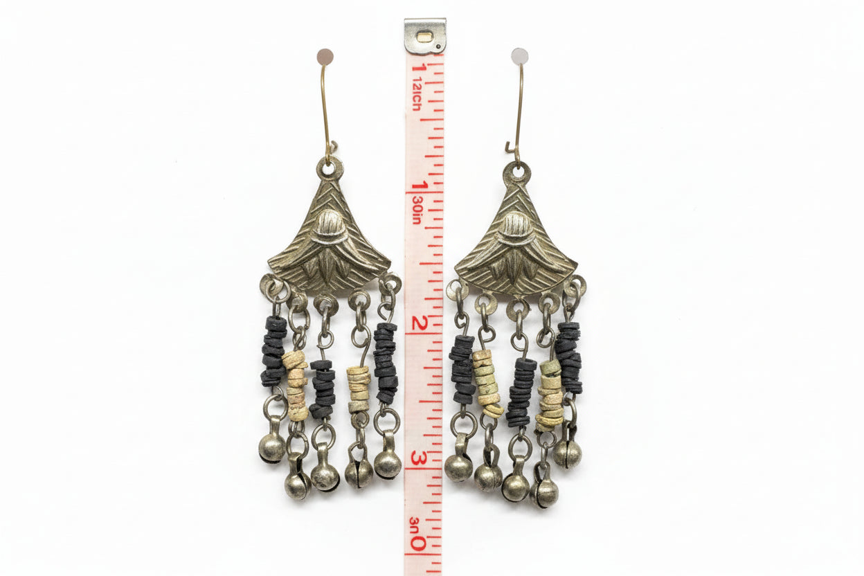 Decorative earrings with beads and charms on a white card with a measuring tape for scale.