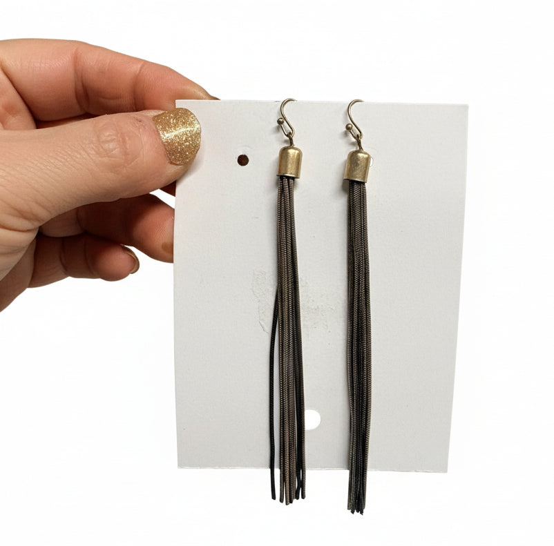 Two tassels on a white card held by a hand with a gold ring.