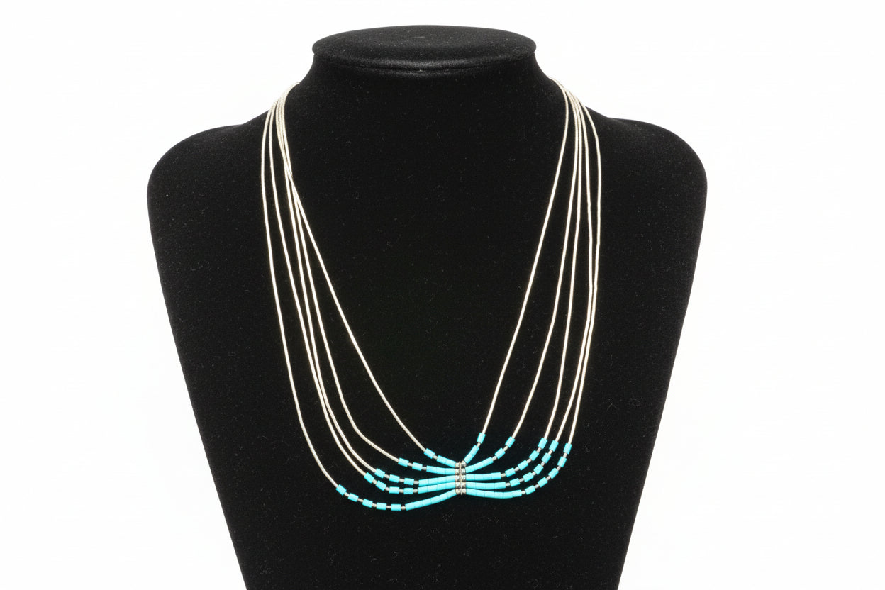 Sterling silver necklace with turquoise beads on a black stand.