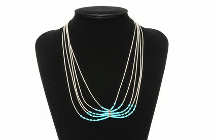 Sterling silver necklace with turquoise beads on a black stand.