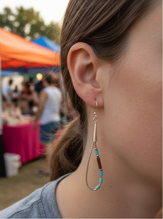 Person wearing earrings with a blurred background of outdoor market stalls.