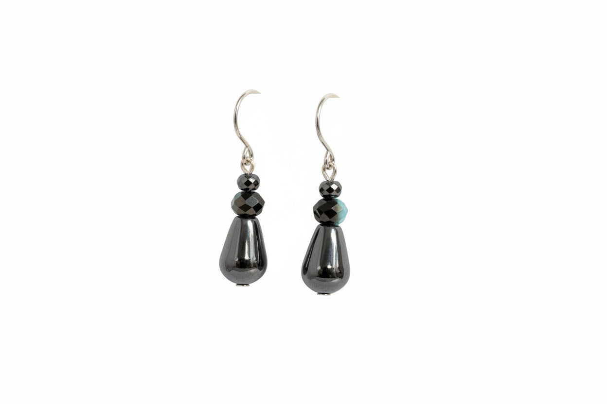 Pair of black teardrop earrings on a white surface with a blurred background