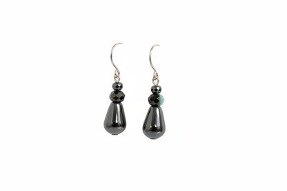 Pair of black teardrop earrings on a white surface with a blurred background