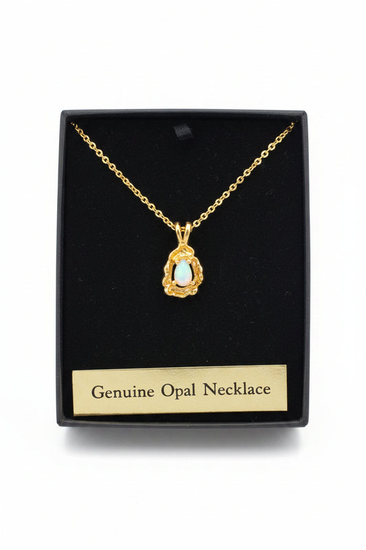 Gold necklace with a pendant on a black card labeled 'Genuine Opal Necklace' next to a bottle of water.