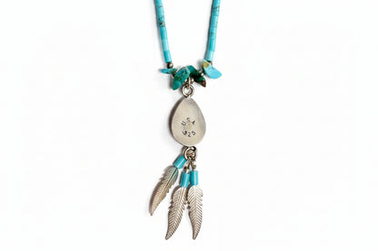 Necklace with silver pendant and feather-shaped charms on a light gray background