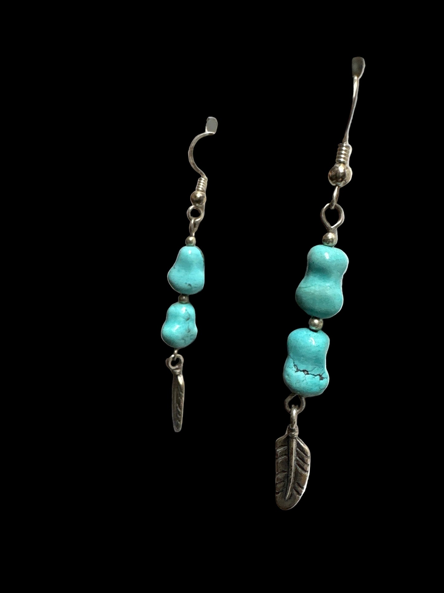 Turquoise beaded earrings on a display card held by a person.