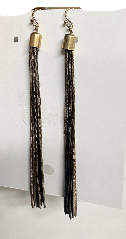 Hand holding a card with two pairs of earrings on a bathroom background