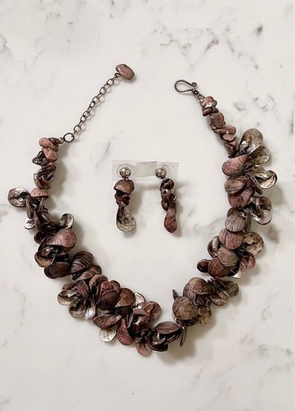 A necklace and earrings set featuring clam shell-like adornments on a white marble surface.
