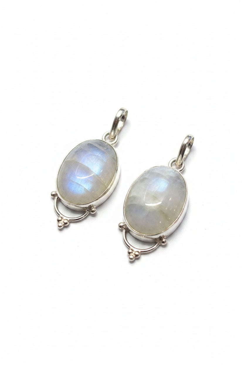 Two silver pendants with moonstones on a white surface.