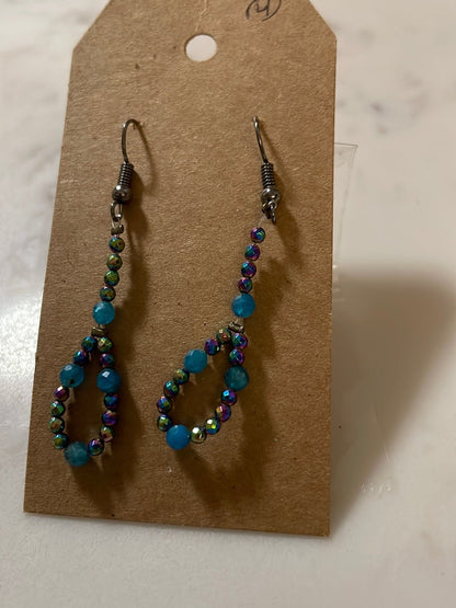 A pair of blue multi-faceted beaded earrings displayed on a cardboard holder.
