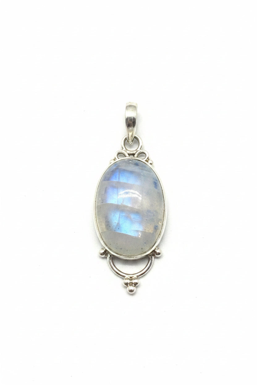 Silver pendant with a stone on a black stone surface, with a red cable and gray object in the background.