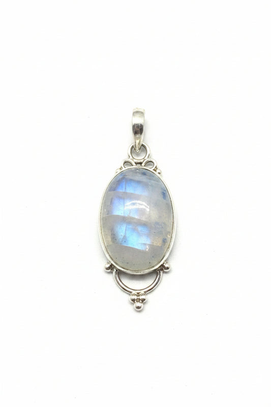 Silver pendant with a stone on a black stone surface, with a red cable and gray object in the background.
